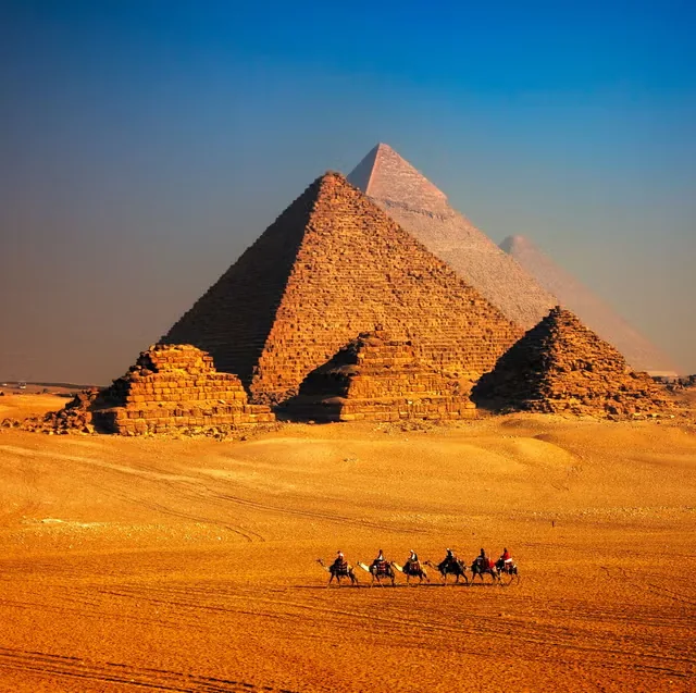 Egypt – Pyramids of Giza with camel caravan in golden desert